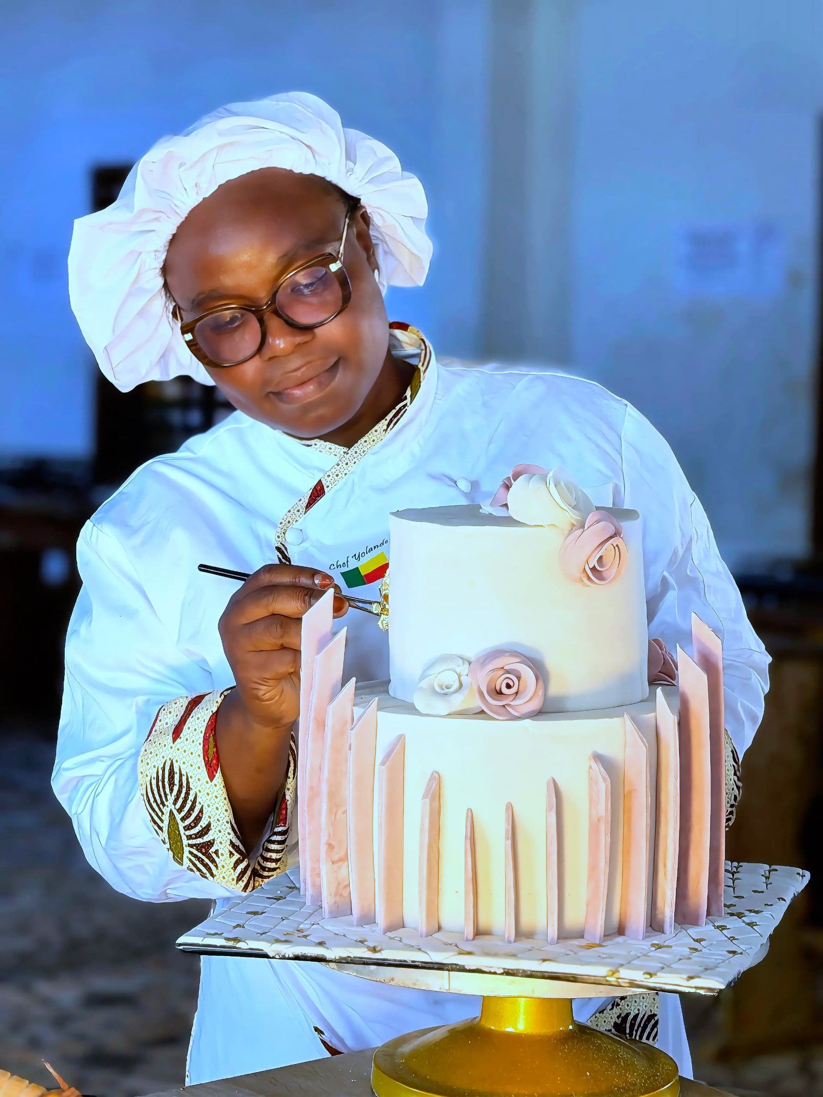 Chef Yollande présentant un magnifique gâteau à étages rose et blanc
