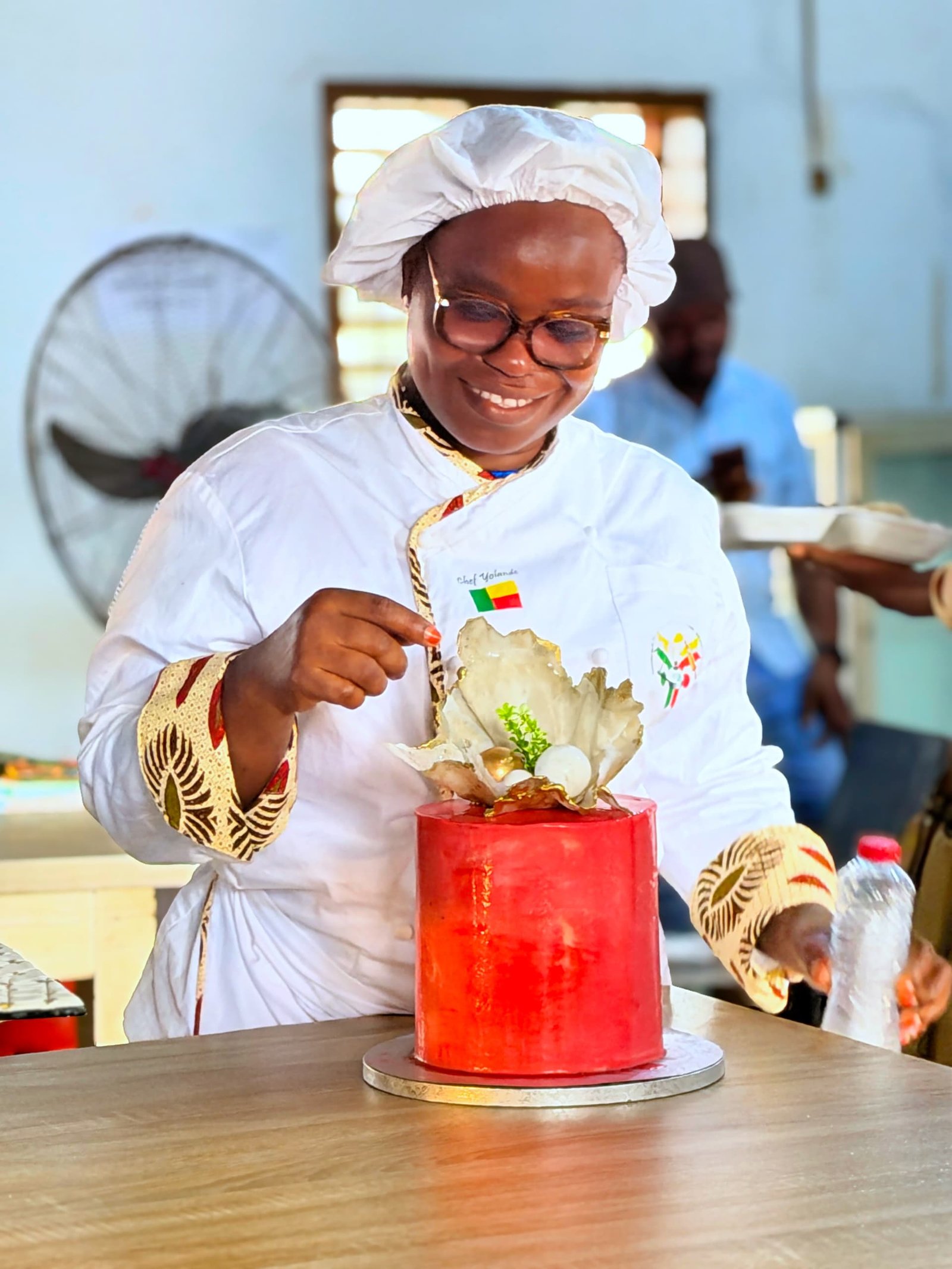 Chef Yollande décorant un gâteau rouge artistique